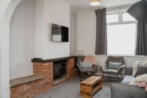 a living room with a brick fireplace and chairs at Valley Park House - By Sigma Stays in Crewe