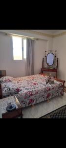 a bedroom with a bed and a table and a mirror at شاليه ارضي بجنينه علي البسين مباشرة in Dawwār al Ḩajj Aḩmad