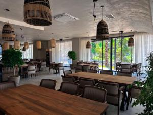 um restaurante com mesas e cadeiras de madeira e janelas em Frojd Kune Resort & Beach Hotel em Shëngjin