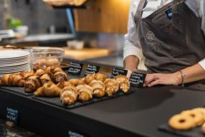 a person in a kitchen with a table of donuts at Olimpia Hotel in Bormio