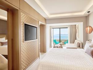 a hotel room with a bed and a tv on a wall at MarBella, Mar-Bella Collection in Agios Ioannis Peristerion