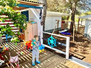 a little boy standing in front of a play house at Mobilehome Adams Glamping - Camp Adriatic in Primošten