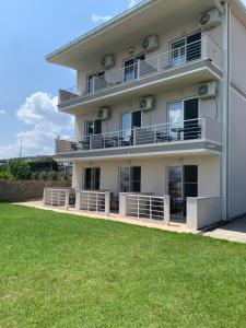 a white building with a lawn in front of it at Sunrise Apartments and Studios in Star Dojran