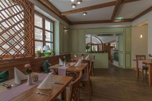 un restaurante con mesas y sillas de madera y ventanas en SPA Hotel Erzherzog Johann, en Bad Aussee