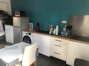 eine Küche mit einer Theke mit Waschmaschine und einem Tisch in der Unterkunft Petit studio proche de l’aéroport Charles de Gaulle in Villepinte