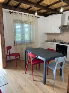 una cocina con mesa negra y sillas rojas en Appartamento da Patrizia, en Simaxis
