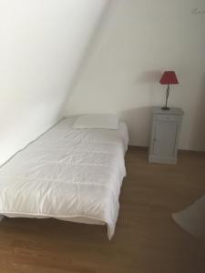 ein Schlafzimmer mit einem weißen Bett und einer Lampe auf einem Nachttisch in der Unterkunft LES GABARES in Gohier
