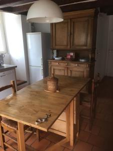 eine Küche mit einem Holztisch und einem Kühlschrank in der Unterkunft LES GABARES in Gohier