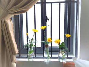 Tres jarrones con flores amarillas sentados en el alféizar de la ventana en GREEN TOWN hotel HỘI AN en Hoi An