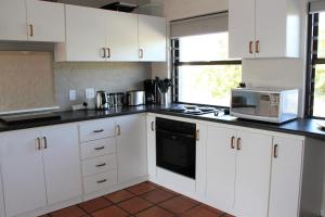 a kitchen with white cabinets and a microwave at 36 @ Plett! in Plettenberg Bay
