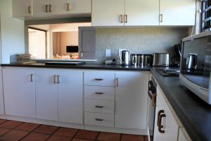 a kitchen with white cabinets and a black counter top at 36 @ Plett! in Plettenberg Bay