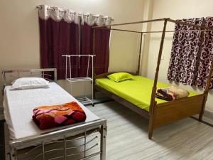 a bedroom with two beds and a canopy bed at Vamoose S Das Homestay in Agartala