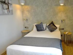 1 dormitorio con 1 cama blanca y 2 almohadas en Hotel Lloret Ramblas, en Barcelona