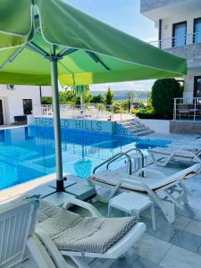 a swimming pool with chairs and an umbrella at Splandid apartment by the sea in Sozopol