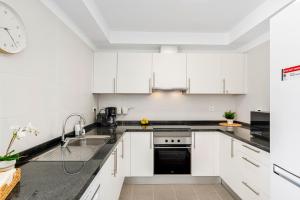 una cucina con mobili bianchi e un lavandino di MEDANO4YOU La Jaquita Terrace Holiday Home a El Médano
