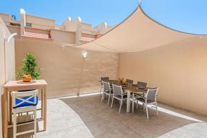 un patio con tavolo e sedie sotto una tenda. di MEDANO4YOU La Jaquita Terrace Holiday Home a El Médano