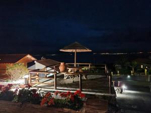 a picnic table with an umbrella and flowers at night at Lucy's Rosegarden in Urzelina