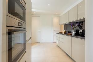 uma cozinha com armários brancos e electrodomésticos de aço inoxidável em Sweet Inn - Wagram em Paris