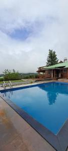 a large blue swimming pool in front of a house at Highgarden Villa in Mahabaleshwar