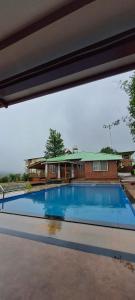 a swimming pool in front of a house at Highgarden Villa in Mahabaleshwar