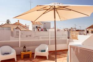 un patio avec deux chaises et un parasol sur le toit dans l'établissement Casa do Terreiro, à Tavira