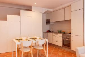 a kitchen with white cabinets and a table and chairs at Casa do Terreiro in Tavira