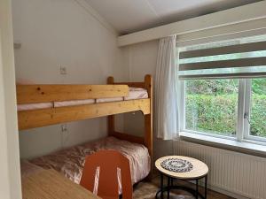 ein Schlafzimmer mit einem Etagenbett, einem Tisch und einem Fenster in der Unterkunft Achterhoekhuisje De Rode Beuk in Hummelo