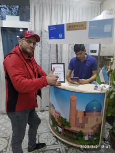 a man standing in front of a table with a sign at Minorai Xurd in Bukhara