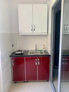 a kitchen with red cabinets and a sink at Hotel Piazza in Sarandë