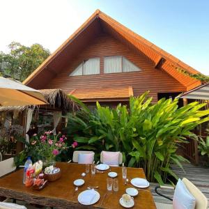 a wooden table with plates on it in front of a house at the NOW by Kru Se in Ban Muang Pha