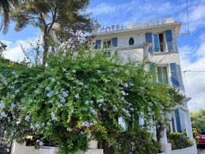 a building with blue flowers in front of a tree at Hotel Albert 1er in Cannes