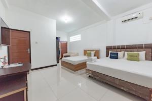 a large bedroom with two beds and a sink at Urbanview Hotel 99 Syariah Banjarbaru by RedDoorz in Martapura