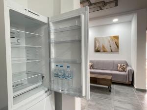 una nevera con botellas de agua y un sofá en 4-bedroom Family apartment in the center of Athens, en Atenas