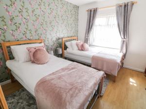 2 camas en una habitación con papel pintado floral en Peter's Farmhouse, en Cookstown