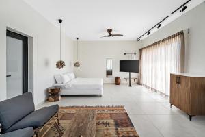 a white living room with a couch and a tv at Hotel Anilevich Mansion in Beer Sheva