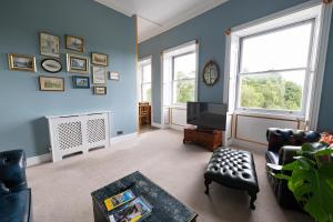 uma sala de estar com um sofá e uma televisão e duas janelas em Crescent Green em Bath