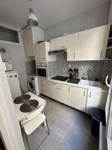 a kitchen with white cabinets and a table and a sink at Charmant Appartement Parisien in Paris