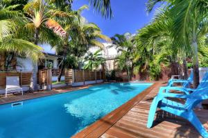 - une piscine avec des chaises bleues et des palmiers dans l'établissement Les nids d'Elo, à Saint-Leu