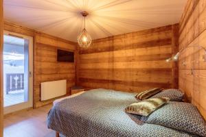 - une chambre avec un lit dans une pièce dotée de murs en bois dans l'établissement Beautiful wooden chalet in La Plagne, à Aime La Plagne