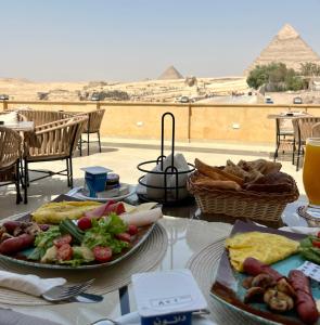 The Gate Hotel Front Pyramids & Sphinx View في القاهرة: طاوله مع صحن طعام واهرامات