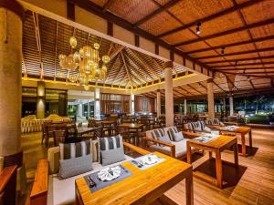 ein Restaurant mit Holztischen und -stühlen sowie einem Kronleuchter in der Unterkunft Kacha Resort & Spa, Koh Chang - SHA Extra Plus in Ko Chang