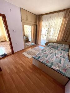 een slaapkamer met een bed en een houten vloer bij Bell House in Moisei
