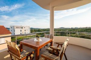 a balcony with a wooden table and chairs at Seaview Apartments Tihi in Vodice
