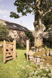 a wooden gate and a tree in front of a building at Eastside Steading - Family barn in the Pentland Hills, Edinburgh in Penicuik