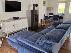 a living room with a blue couch and a tv at Ferienhaus Wentowseeblick in Zehdenick