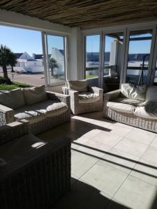 - un salon avec des canapés, des tables et des fenêtres dans l'établissement The Tides Holiday Home, à St Helena Bay