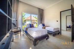 1 Schlafzimmer mit 2 Betten, einem TV und einem Spiegel in der Unterkunft Villa Akasa Segara Beachfront and Private Pool in Banjar