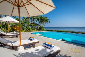 einen Pool mit 2 Stühlen und einem Sonnenschirm in der Unterkunft Villa Akasa Segara Beachfront and Private Pool in Banjar