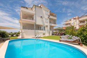 a villa with a swimming pool in front of a building at Apartments Tihi III in Vodice
