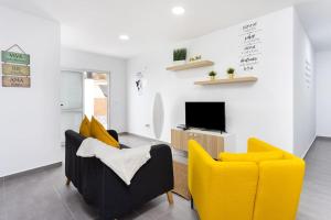 sala de estar con 2 sillas amarillas y TV en Bryson Home, en San Juan del Reparo